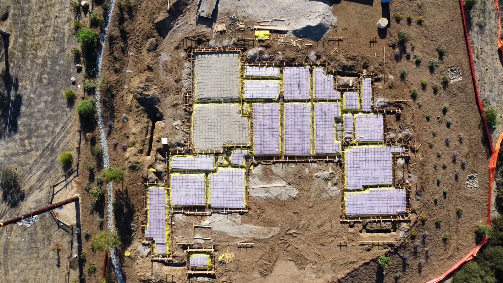 Aerial view of reinforcing mats on vapor retarder within formed foundation bays