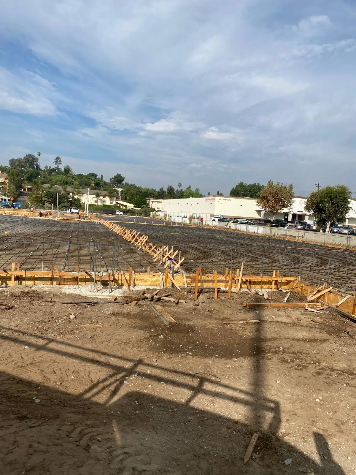 Reinforced building pad with formwork and survey stakes on a public-scale site